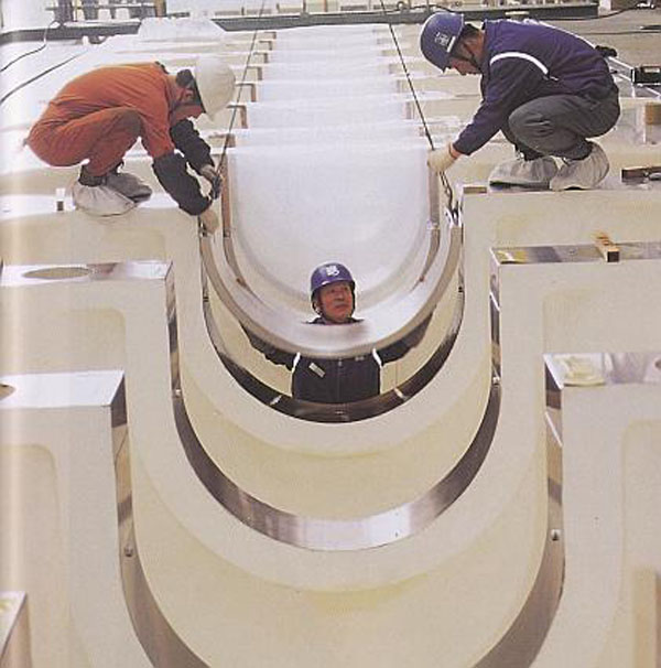 Εργάτες καλυπτουν τα έδρανα του στροφαλοφόρου άξονα σε έναν δίχρονο diesel.jpg